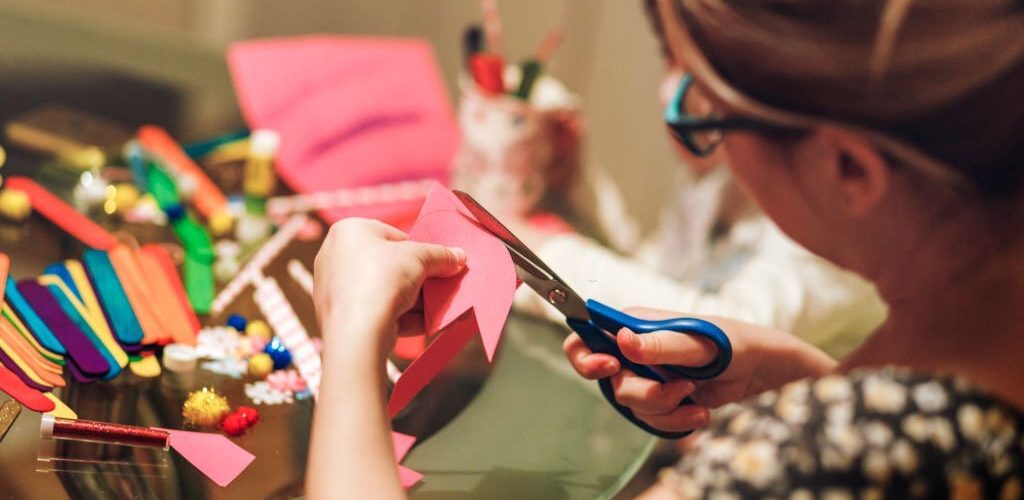 Young woman is crafting painted flowers at home. Genuine scene, real people.