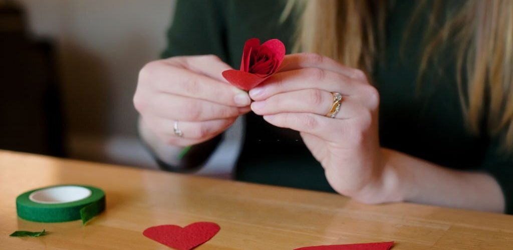 Female hands construct a paper flower.