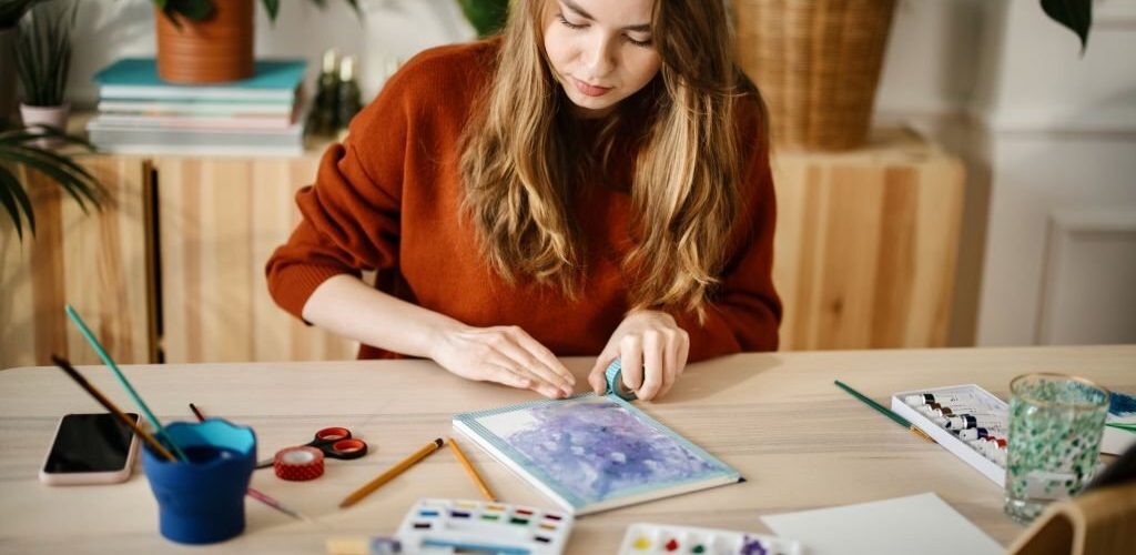 Millennial woman watching tutorials on digital tablet about watercolour painting