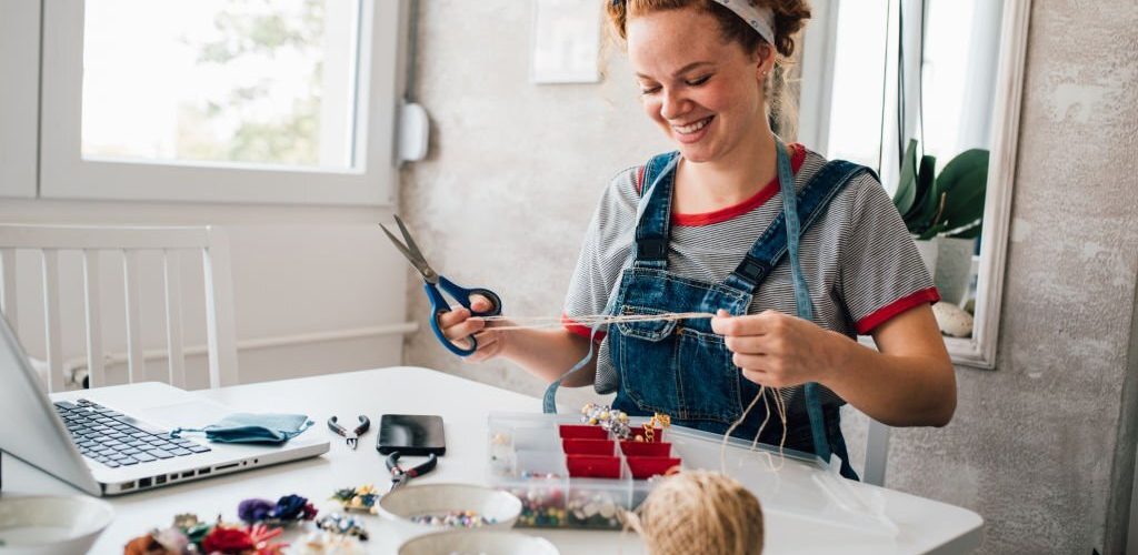 Young woman making jewelry at home.